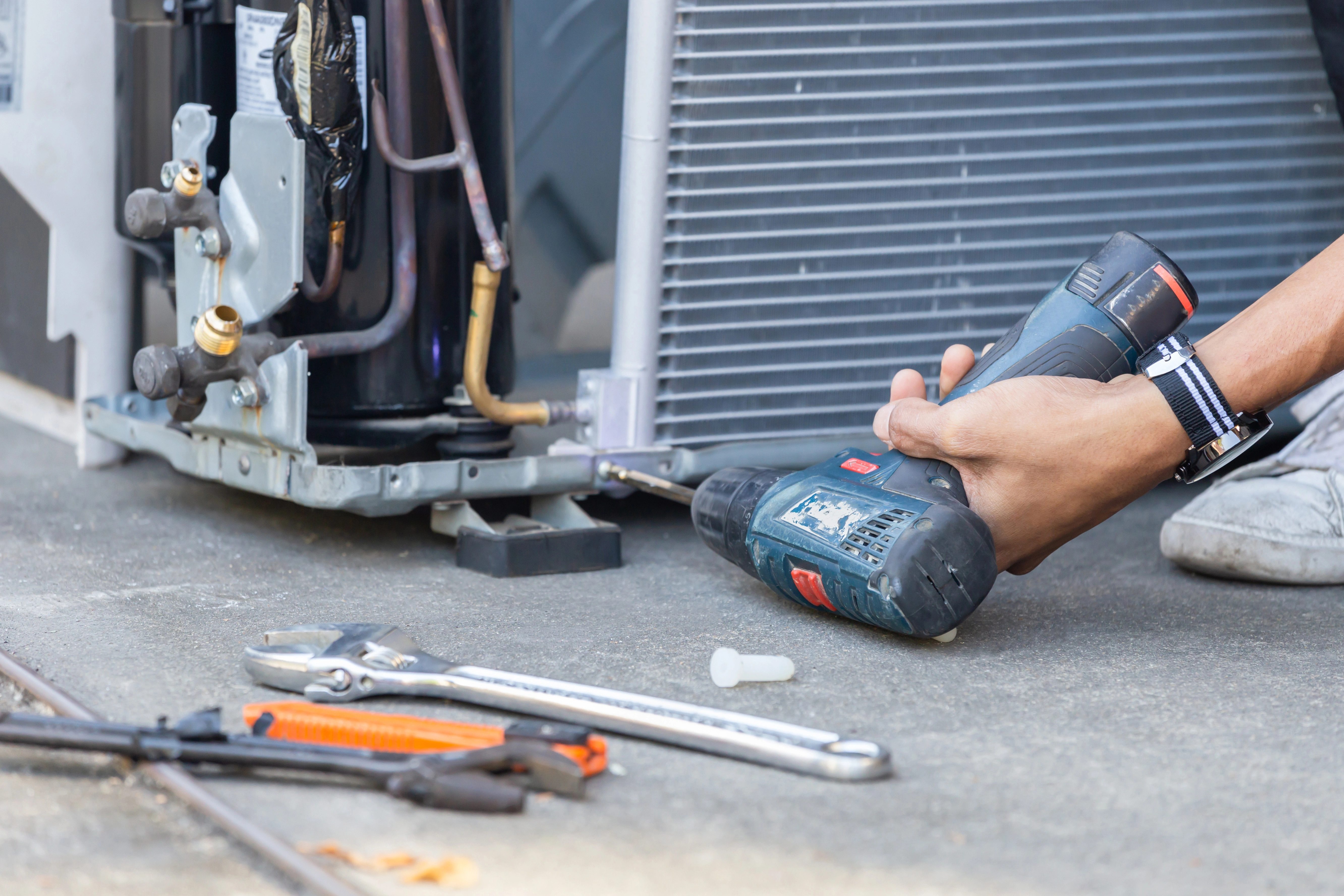 Air Dynamics of Tulsa technician performing an AC repair on an outdoor compressor unit.
