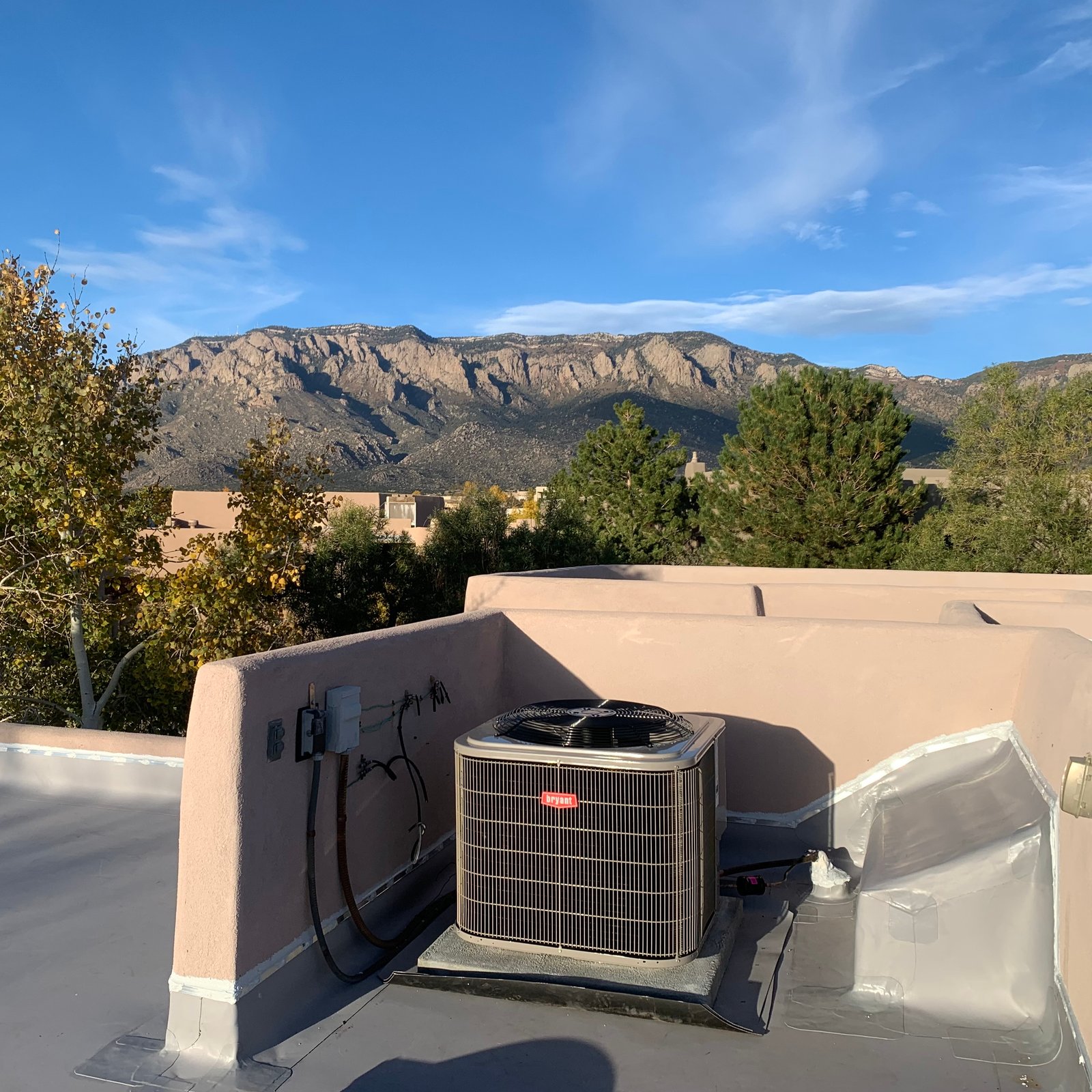 A modern gray residential air conditioner unit installed on a concrete slab next to a home in Tulsa, OK.